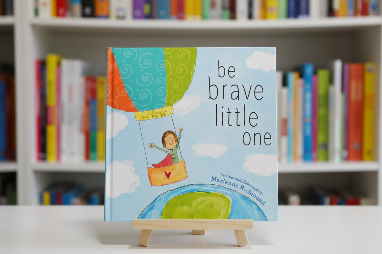 Book cover of 'Be Brave Little One' with a child in a hot air balloon.