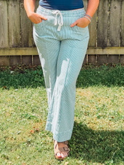 Woman standing outdoors in a backyard with a wooden fence and trees in the background.